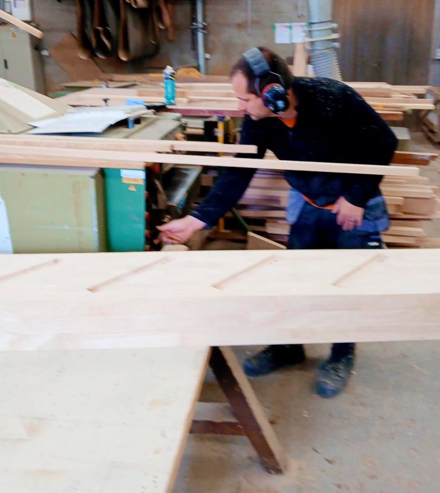 Menuisier façonnant une grande planche de bois dans l'atelier
